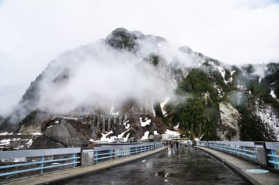 雲霧繚繞的黑部水壩與殘雪山巒