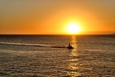船帆石夕陽下的海上水上摩托車剪影