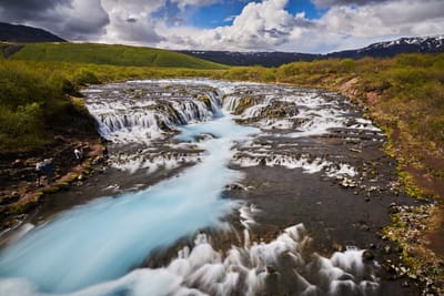 藍色秘境瀑布湍急水流與翠綠山丘景致