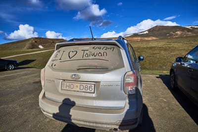車窗上寫著我愛台灣的灰塵車輛與遠方火山地景