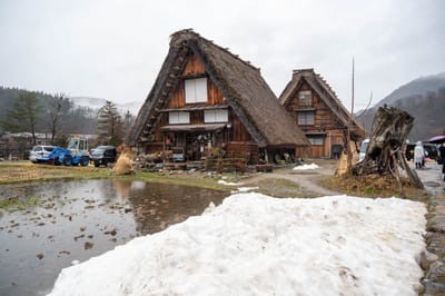 殘雪映襯下的傳統茅草屋舍