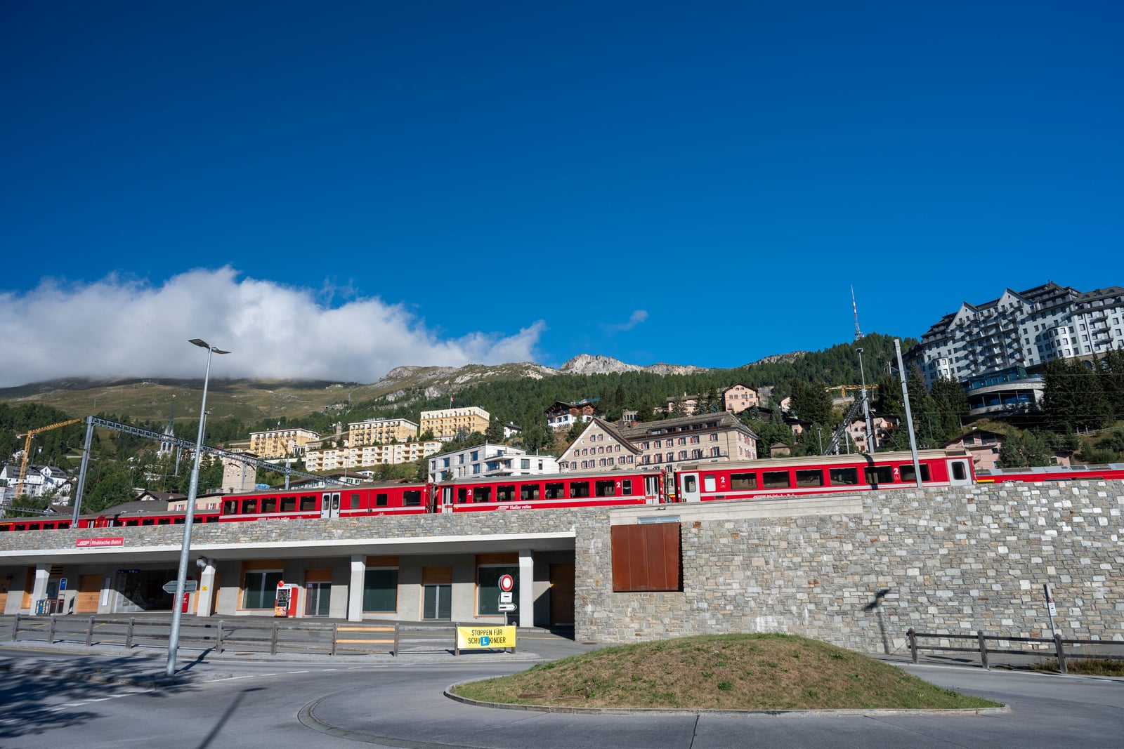 湛藍晴空下行駛於山城的紅色列車與建築群｜2024/09 瑞士