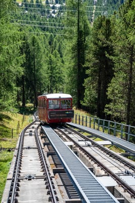 綠意山林間行駛的紅色高山登山纜車
