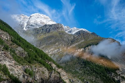 藍天白雲下覆雪山峰與山谷雲霧