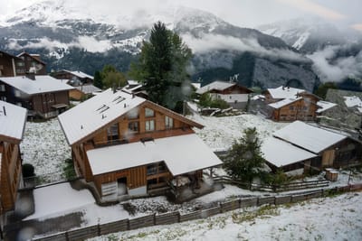 初雪覆蓋的山村木屋與遠方雪山