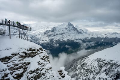 懸崖觀景台上的漫步遊客與壯麗雪山