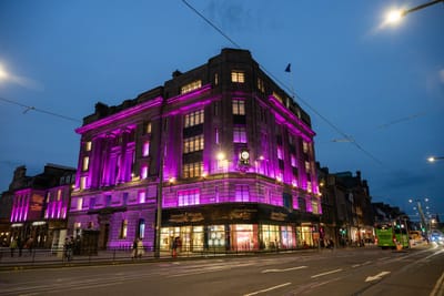 愛丁堡街頭夜色中亮起紫紅色燈光的古典建築與特色鐘樓