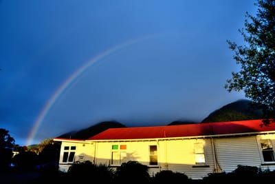 夕陽餘暉下小屋與清晰彩虹