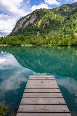 綠意山景與藍綠色湖水倒影木棧道